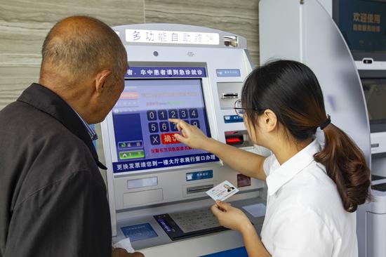 服務(wù)人員通過掛號自助機為老人預(yù)約專家。潘迎霞 攝